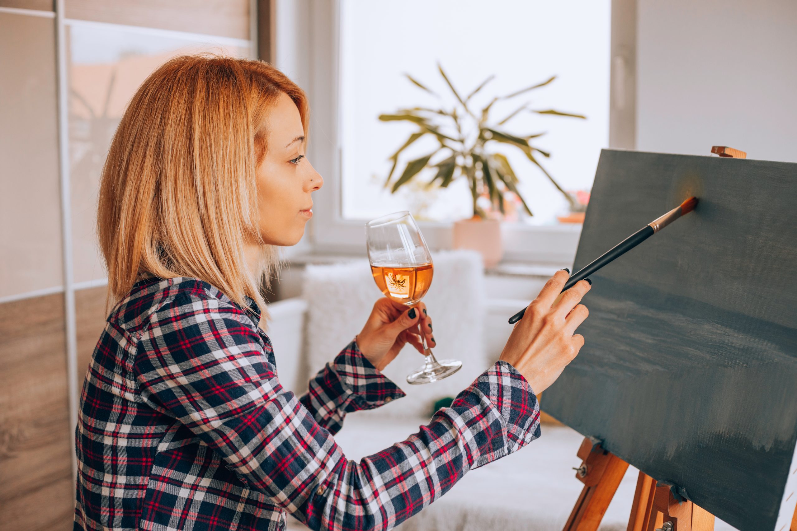 Círculo creativo con vino y música - Ambiente íntimo con participantes pintando entre copas y melodías suaves